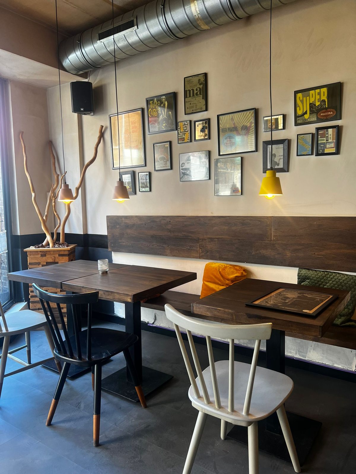 Houten banken met kussens en een muur vol Italiaanse vintage affiches